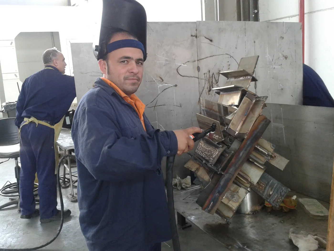 Alumno en el taller con la torcha y sus probetas soldadas